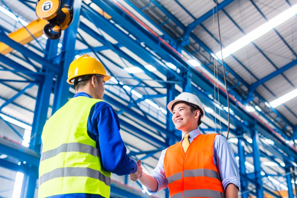 two people wearing hard hats shaking hands